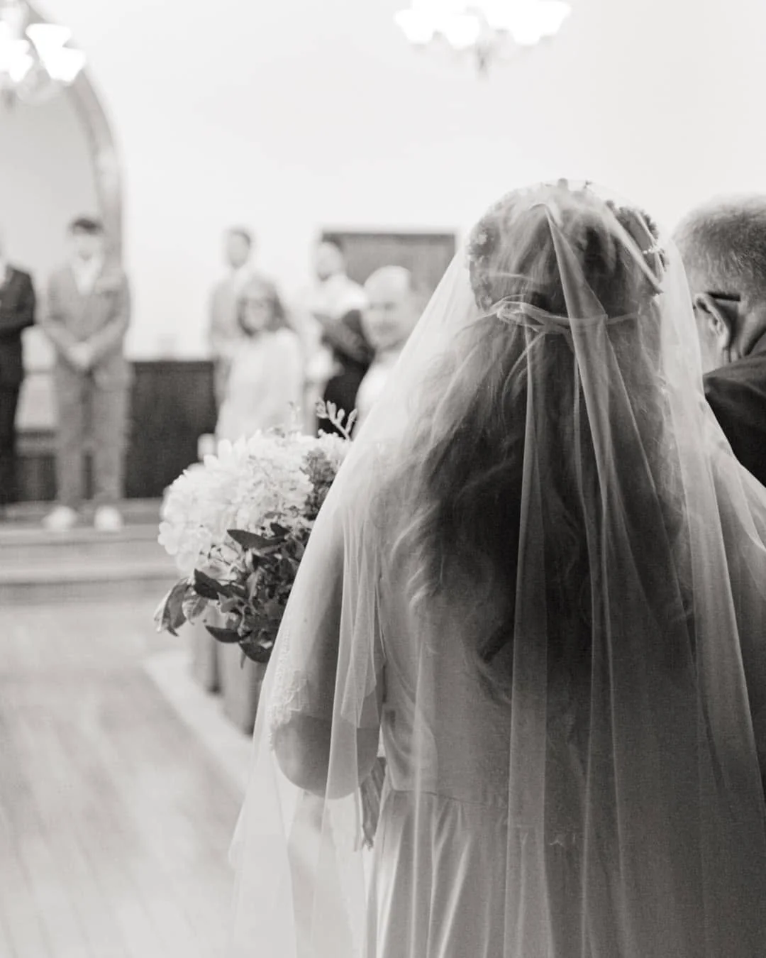 A bride walking down the aisle, in black and white