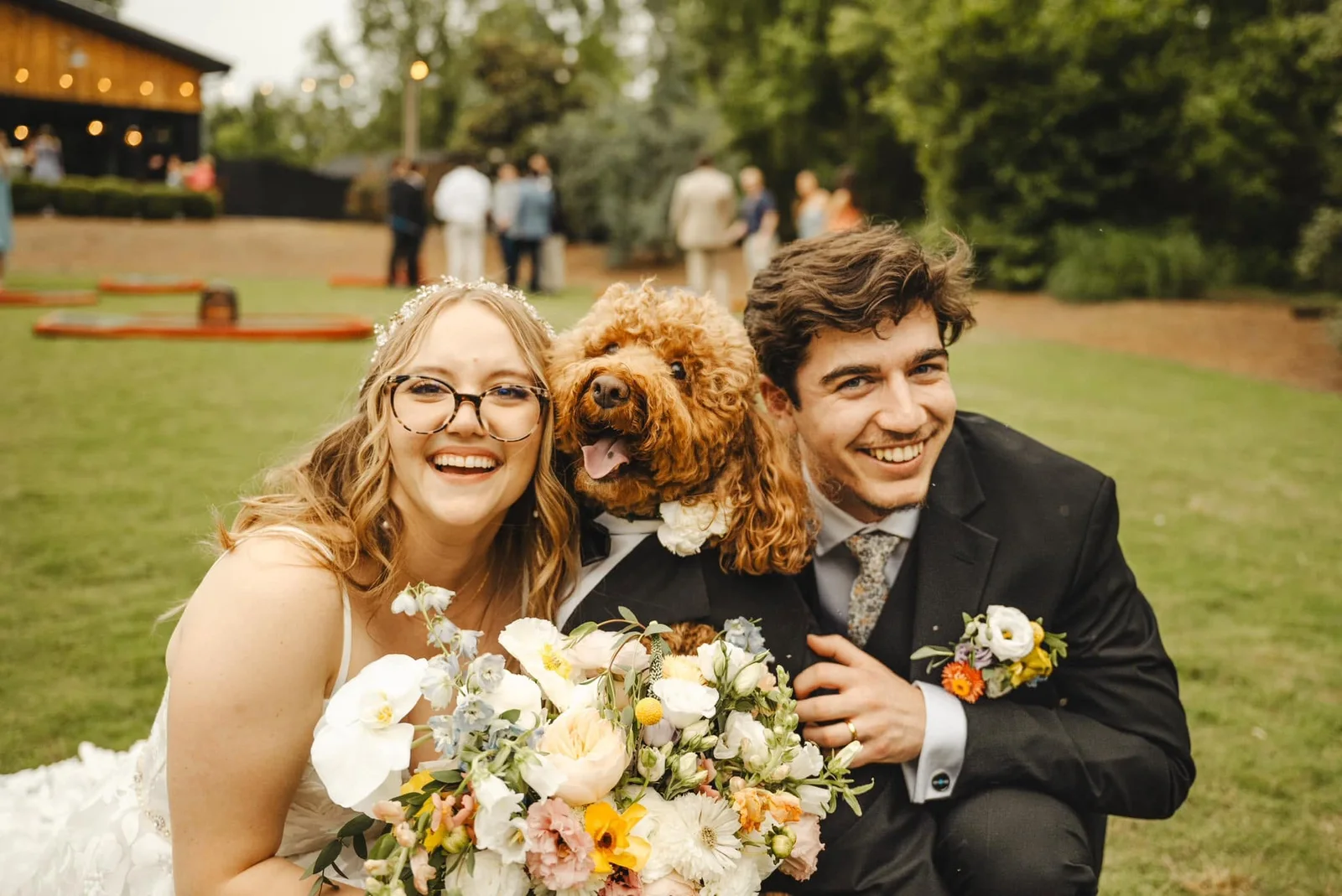 A couple with their golden doodle and a bouquet